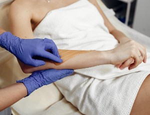 esthetician performing wax hair removal treatment